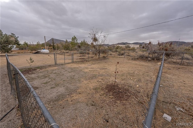 view of yard with a rural view, a mountain view, and fence