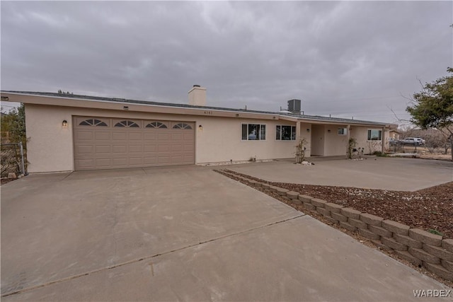 ranch-style house with a garage, driveway, central air condition unit, and stucco siding