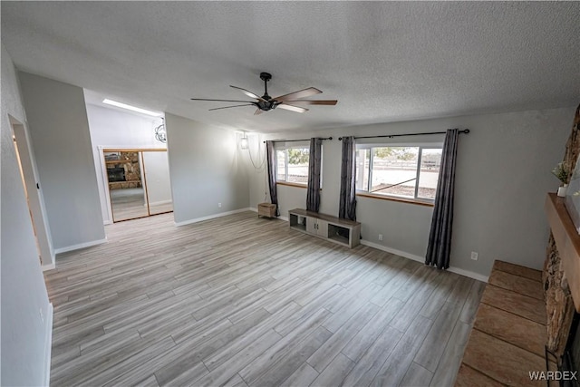 unfurnished living room featuring a fireplace, light wood finished floors, a ceiling fan, vaulted ceiling, and a textured ceiling