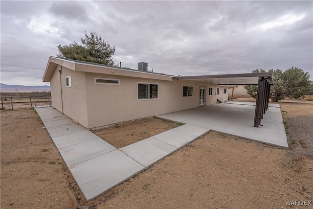 rear view of house featuring cooling unit, a patio, fence, and stucco siding