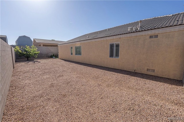 view of property exterior featuring stucco siding, fence private yard, and a tile roof