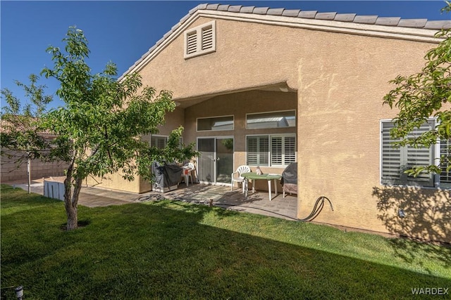 rear view of house with a lawn, a patio, fence, and stucco siding