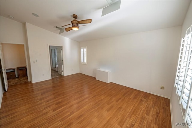 empty room featuring ceiling fan, vaulted ceiling, light wood-type flooring, and visible vents