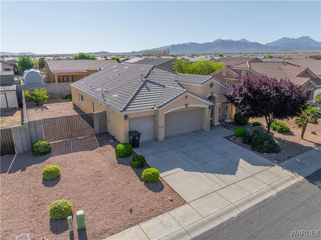 view of front facade with a gate, fence, concrete driveway, an attached garage, and stucco siding