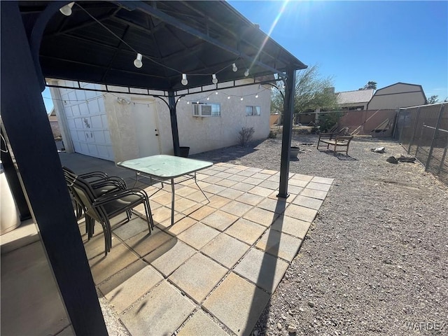 view of patio / terrace featuring an AC wall unit, a fenced backyard, and a gazebo