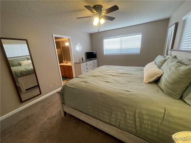 bedroom with baseboards, a ceiling fan, ensuite bath, a textured ceiling, and dark carpet