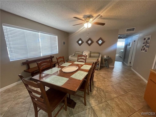 dining space featuring ceiling fan, a textured ceiling, light tile patterned flooring, visible vents, and baseboards