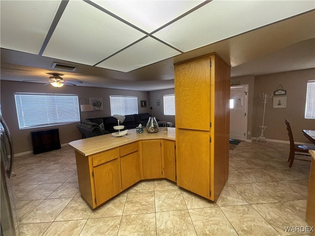 kitchen with ceiling fan, a peninsula, visible vents, open floor plan, and light countertops