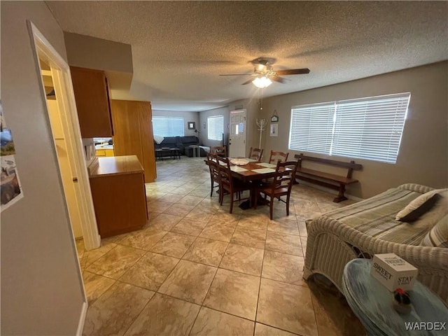 dining space featuring a ceiling fan, a textured ceiling, and light tile patterned floors