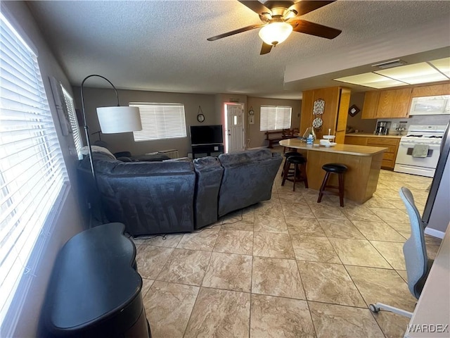 living area featuring a textured ceiling, ceiling fan, light tile patterned flooring, and visible vents