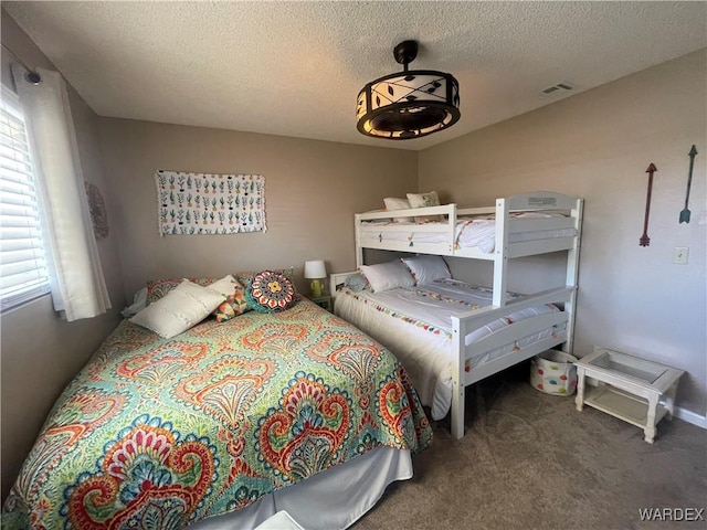 carpeted bedroom with visible vents and a textured ceiling