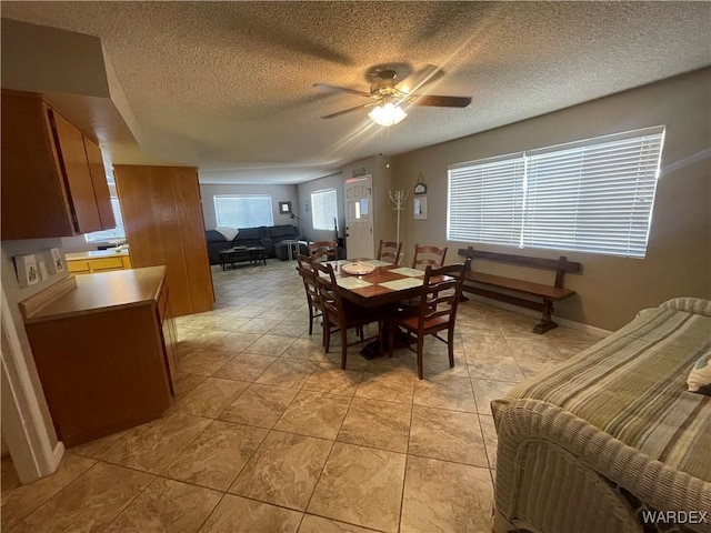 dining room with a ceiling fan, light tile patterned flooring, a textured ceiling, and baseboards