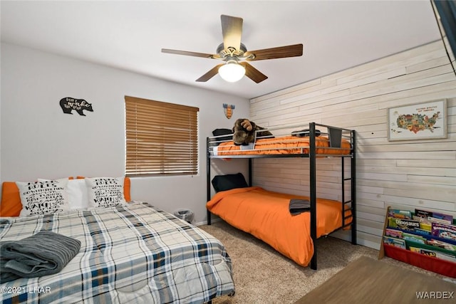 bedroom with wooden walls, ceiling fan, and carpet floors