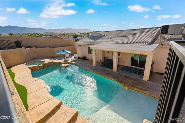 view of pool featuring a pool with connected hot tub, central air condition unit, a fenced backyard, a patio area, and a mountain view