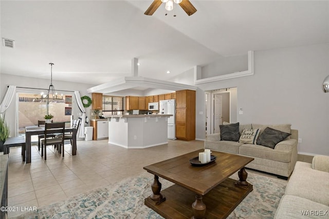 living area featuring baseboards, vaulted ceiling, light tile patterned floors, visible vents, and ceiling fan with notable chandelier