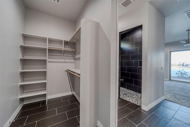 spacious closet featuring wood finish floors, visible vents, and a ceiling fan