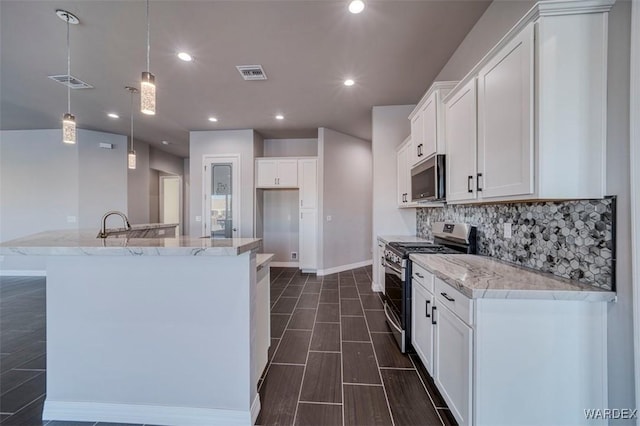 kitchen with appliances with stainless steel finishes, white cabinetry, hanging light fixtures, and light stone counters