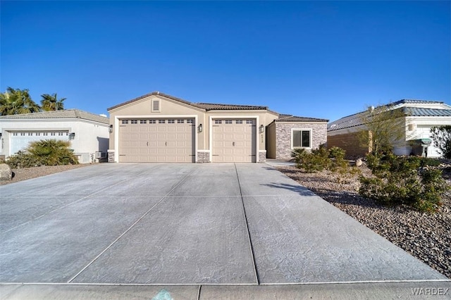 view of front of home with stucco siding, an attached garage, stone siding, driveway, and a tiled roof