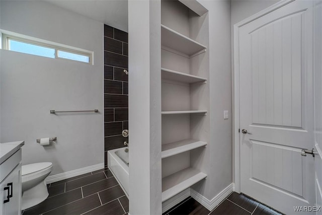 bathroom featuring wood finish floors, vanity, toilet, and baseboards