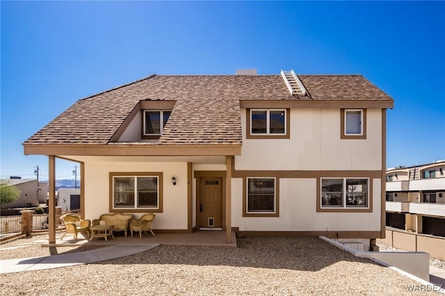 view of front of property with a shingled roof, fence, and a patio