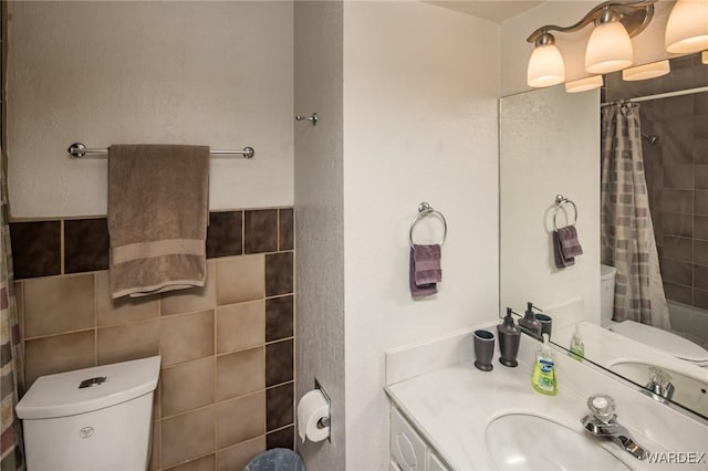 full bathroom with toilet, vanity, and tile walls