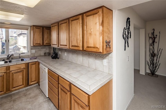 kitchen with tile countertops, tasteful backsplash, brown cabinetry, and a sink