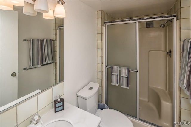 bathroom featuring toilet, an enclosed shower, and vanity