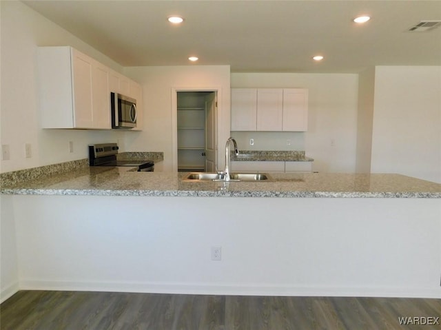 kitchen featuring white cabinets, a peninsula, stainless steel appliances, and a sink