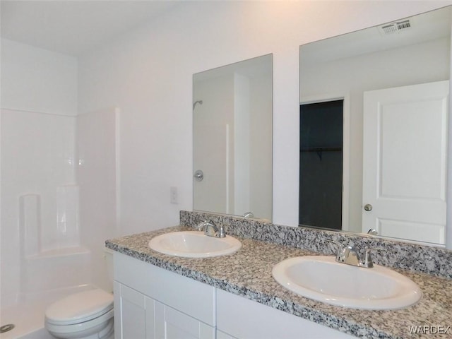 full bathroom with a walk in closet, visible vents, a sink, and toilet