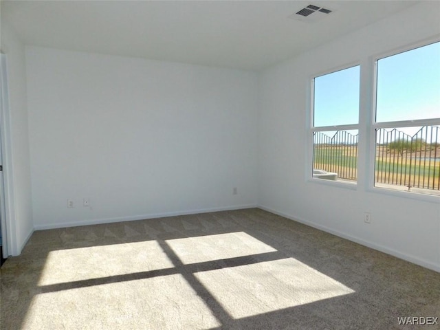 unfurnished room with dark carpet, visible vents, and baseboards