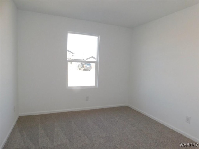 carpeted spare room featuring baseboards