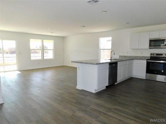 kitchen featuring stainless steel appliances, open floor plan, white cabinetry, and a sink