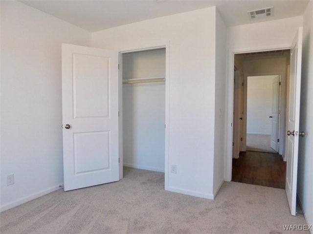 unfurnished bedroom with light carpet, baseboards, visible vents, and a closet