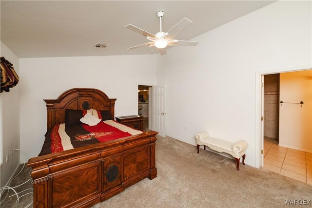 bedroom with high vaulted ceiling, light tile patterned floors, visible vents, and light colored carpet