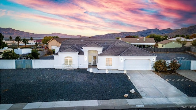 view of front of home with concrete driveway, a fenced front yard, an attached garage, and a mountain view