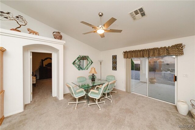 dining space featuring light colored carpet, visible vents, vaulted ceiling, and arched walkways