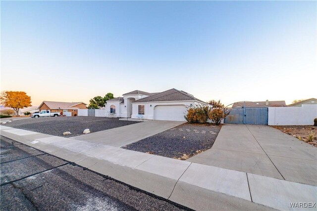 view of front of property featuring an attached garage, fence, concrete driveway, a residential view, and a gate