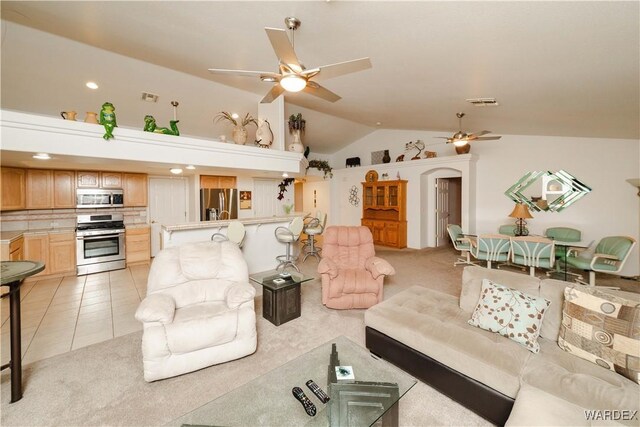 living area featuring arched walkways, ceiling fan, lofted ceiling, and light colored carpet