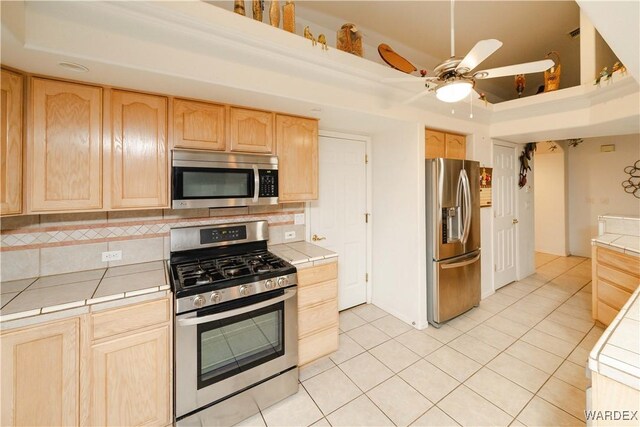 kitchen with tile countertops, light brown cabinets, and appliances with stainless steel finishes