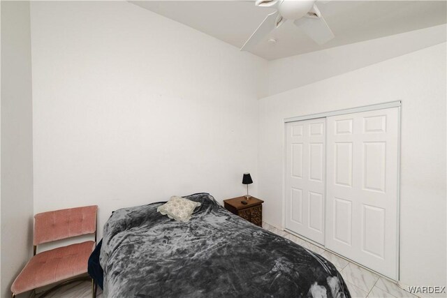 bedroom featuring lofted ceiling, marble finish floor, a ceiling fan, and a closet