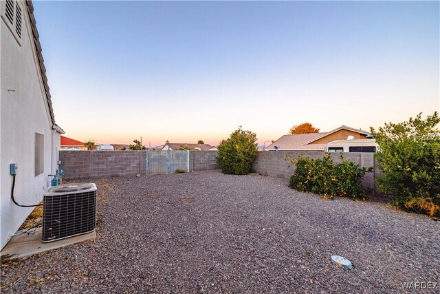 yard at dusk with a fenced backyard, cooling unit, and visible vents