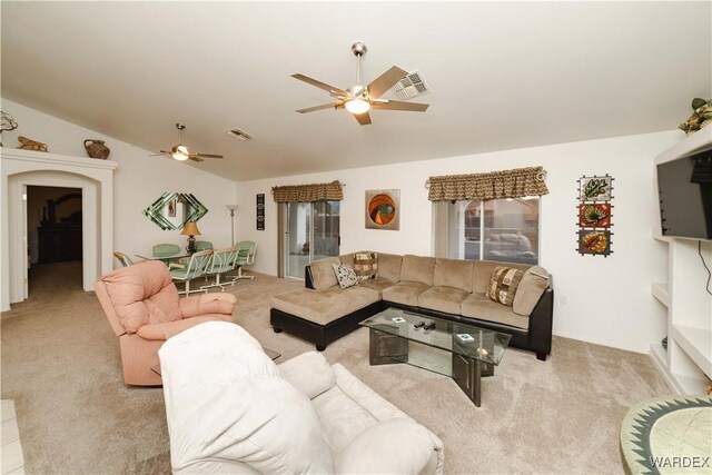 living room with lofted ceiling, ceiling fan, visible vents, and light colored carpet