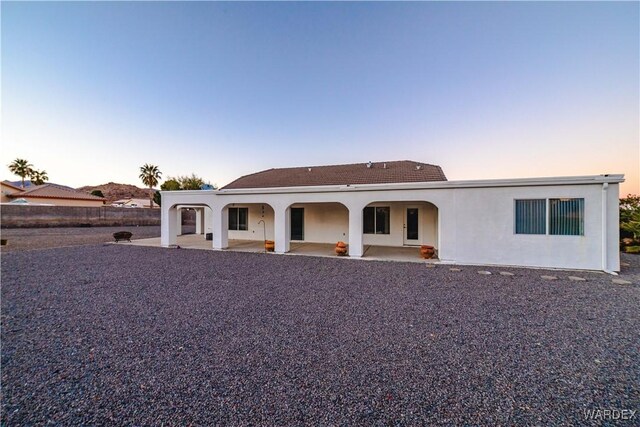 back of property at dusk featuring a patio area and stucco siding