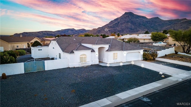 view of front of house with driveway, a fenced front yard, a gate, and a mountain view