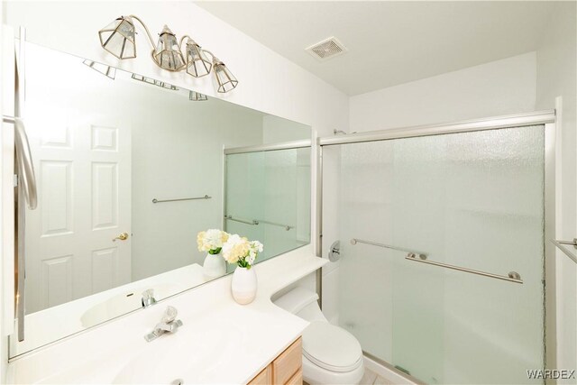 full bathroom with toilet, vanity, a shower stall, and visible vents