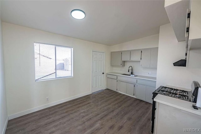 kitchen with dark wood finished floors, light countertops, gray cabinetry, a sink, and baseboards