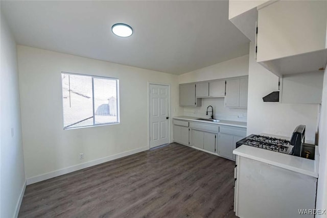 kitchen with range, baseboards, light countertops, and a sink