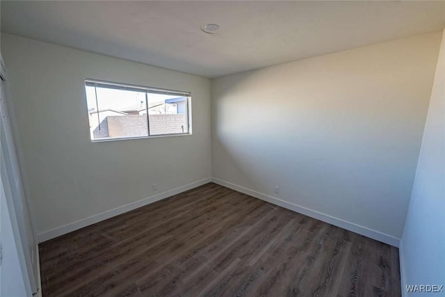 spare room with dark wood finished floors and baseboards