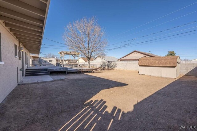 view of yard featuring a storage shed, a fenced backyard, and an outdoor structure