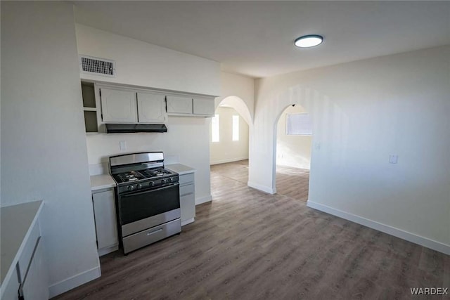 kitchen with visible vents, arched walkways, range with gas cooktop, light countertops, and under cabinet range hood